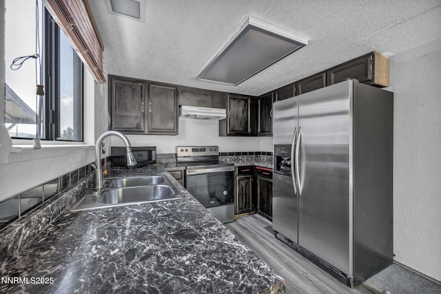 650 E York Way, Sparks, NV 89431 - kitchen featuring appliances with stainless steel finishes, under cabinet range hood, a textured ceiling, light wood finished floors, and dark stone counters