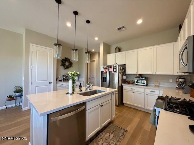 7800 Hoback Dr, Sparks, NV 89436 - kitchen featuring appliances with stainless steel finishes, a sink, light wood-type flooring, light countertops, and white cabinets