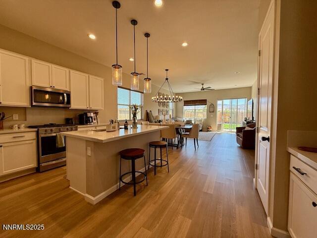 7800 Hoback Dr, Sparks, NV 89436 - kitchen with appliances with stainless steel finishes, open floor plan, wood finished floors, white cabinetry, and a kitchen island with sink