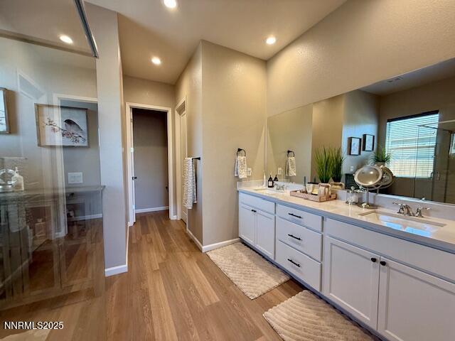 7800 Hoback Dr, Sparks, NV 89436 - bathroom featuring double vanity, wood finished floors, a shower with shower door, baseboards, and recessed lighting