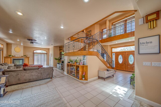 6752 Eagle Wing Cir, Sparks, NV 89436 - tiled living room featuring a glass covered fireplace, stairs, and recessed lighting