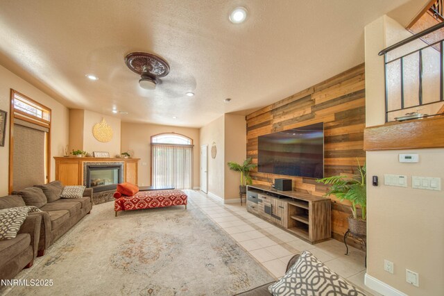 6752 Eagle Wing Cir, Sparks, NV 89436 - living room featuring light tile patterned floors, wooden walls, recessed lighting, a glass covered fireplace, and a textured ceiling