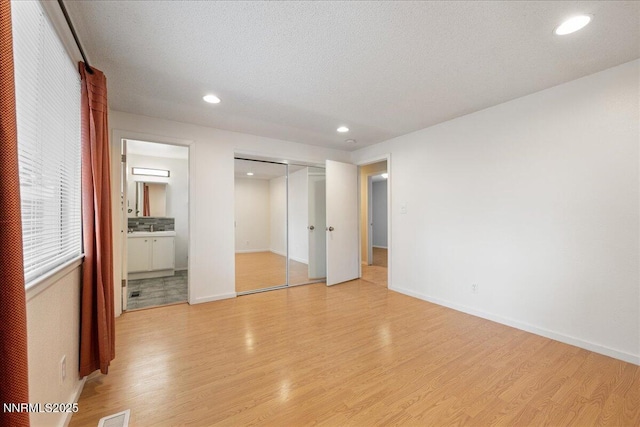 3830 Avocet Ct, Reno, NV 89508 - unfurnished bedroom featuring light wood finished floors, recessed lighting, ensuite bathroom, a closet, and a textured ceiling