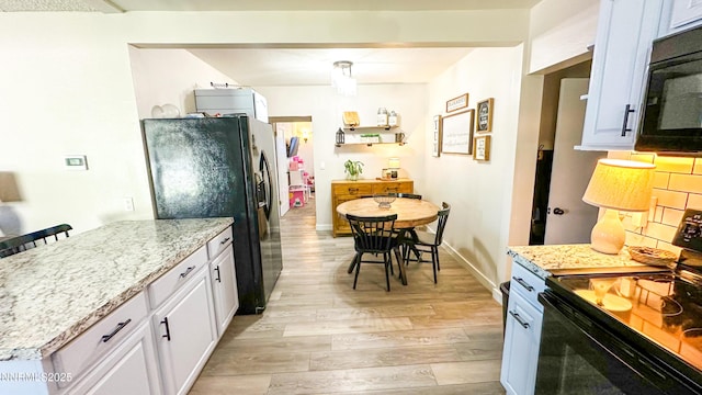 241 W National Ave, Winnemucca, NV 89445 - kitchen featuring black appliances, light wood finished floors, white cabinetry, light stone counters, and baseboards