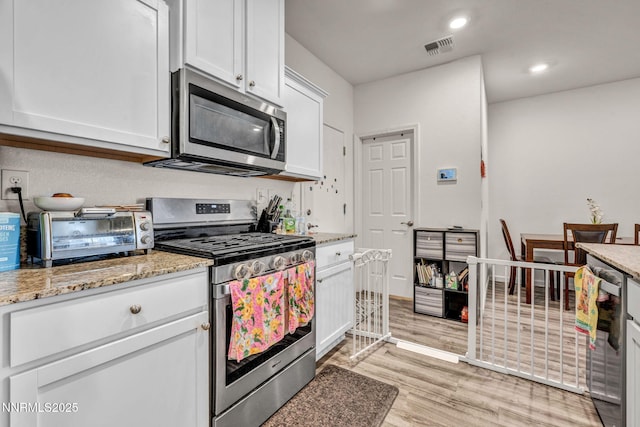 529 Autumn Breeze Cir, Reno, NV 89511 - kitchen featuring appliances with stainless steel finishes, white cabinets, light wood-style floors, light stone countertops, and recessed lighting