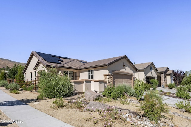 9195 Summertree Ct, Reno, NV 89523 - view of front facade with a garage, solar panels, stucco siding, a tiled roof, and stone siding