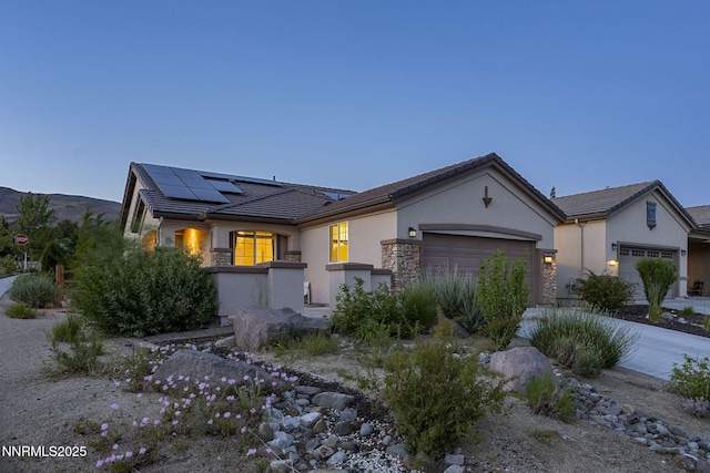 9195 Summertree Ct, Reno, NV 89523 - view of front of home with an attached garage, stucco siding, stone siding, solar panels, and a tiled roof