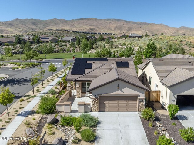 9195 Summertree Ct, Reno, NV 89523 - view of front of property featuring stone siding, driveway, an attached garage, stucco siding, and solar panels