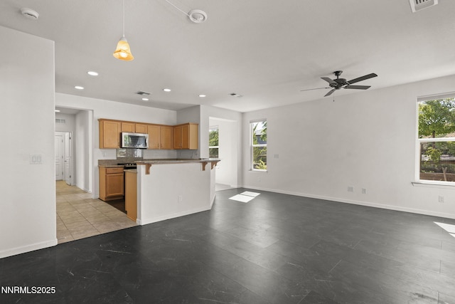 9195 Summertree Ct, Reno, NV 89523 - kitchen featuring stainless steel microwave, a breakfast bar area, open floor plan, recessed lighting, and a ceiling fan