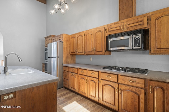 430 E Queen Way, Sparks, NV 89431 - kitchen with stainless steel appliances, a sink, brown cabinets, light wood-style floors, and a high ceiling