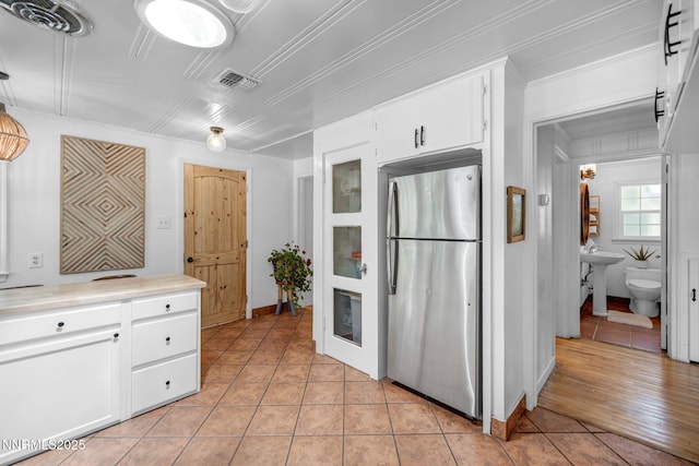 705 Elm St, Carson City, NV 89703 - kitchen featuring freestanding refrigerator, light tile patterned floors, white cabinets, light countertops, and ornamental molding