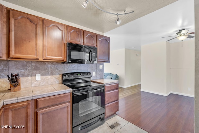 3310 Delna Dr, Sparks, NV 89431 - kitchen with black appliances, decorative backsplash, tile counters, light wood-style floors, and a ceiling fan