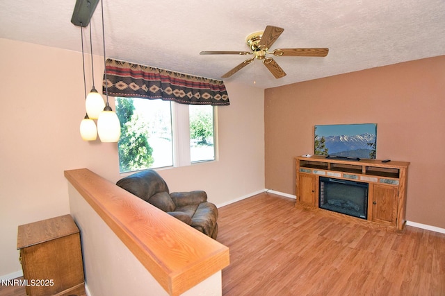 35 Count Fleet Ct, Reno, NV 89502 - living area with a glass covered fireplace, ceiling fan, light wood-style flooring, and a textured ceiling