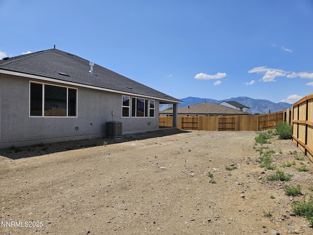 1224 Heybourne Rd, Gardnerville, NV 89410 - rear view of house with a fenced backyard, a mountain view, central AC unit, stucco siding, and a shingled roof