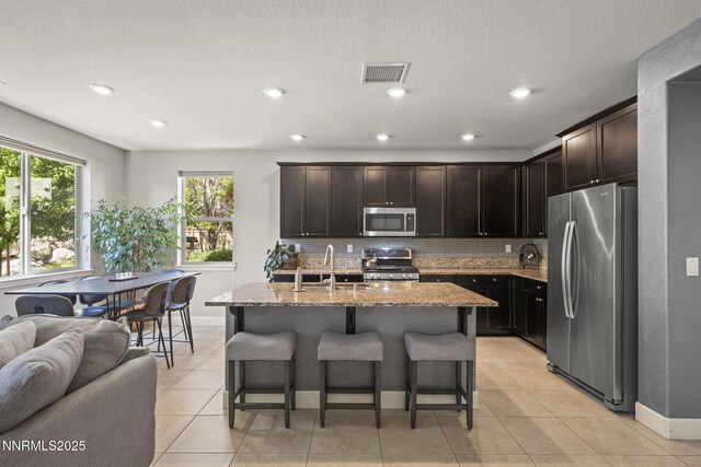1775 Samantha Crest Trl, Reno, NV 89523 - kitchen featuring appliances with stainless steel finishes, a breakfast bar, tasteful backsplash, light stone countertops, and open floor plan