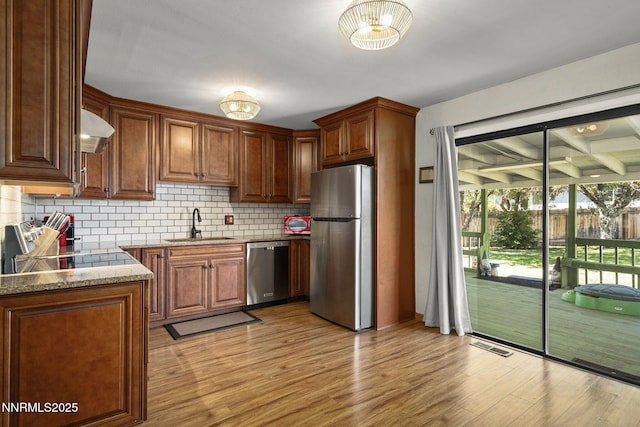 3505 Everett Dr, Reno, NV 89503 - kitchen with stainless steel appliances, tasteful backsplash, wall chimney exhaust hood, light wood-style flooring, and light stone counters