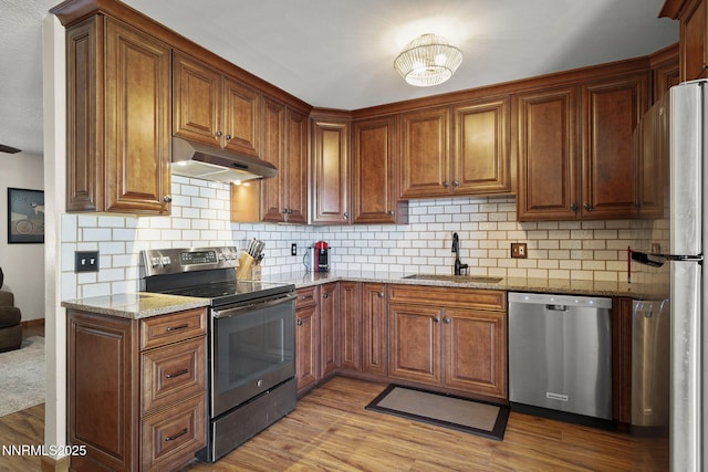 3505 Everett Dr, Reno, NV 89503 - kitchen featuring appliances with stainless steel finishes, under cabinet range hood, light stone counters, and decorative backsplash