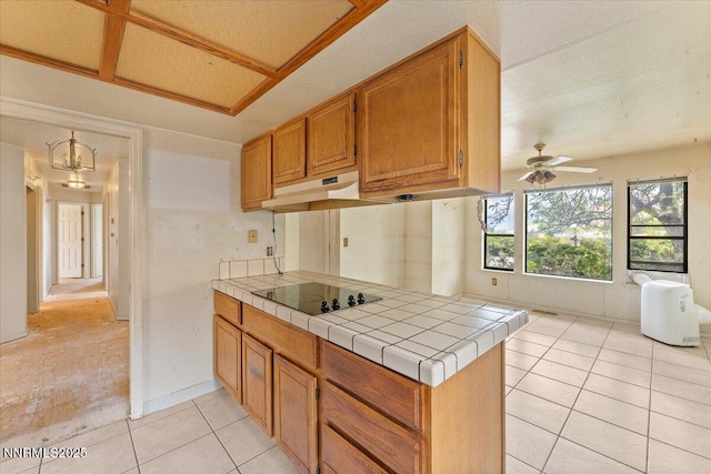1372 Laser Ct, Sparks, NV 89436 - kitchen with black electric cooktop, under cabinet range hood, tile countertops, light tile patterned flooring, and ceiling fan