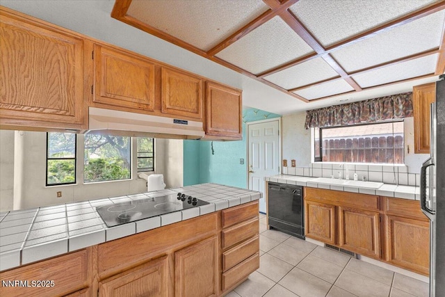 1372 Laser Ct, Sparks, NV 89436 - kitchen featuring black appliances, tile countertops, under cabinet range hood, light tile patterned floors, and healthy amount of natural light
