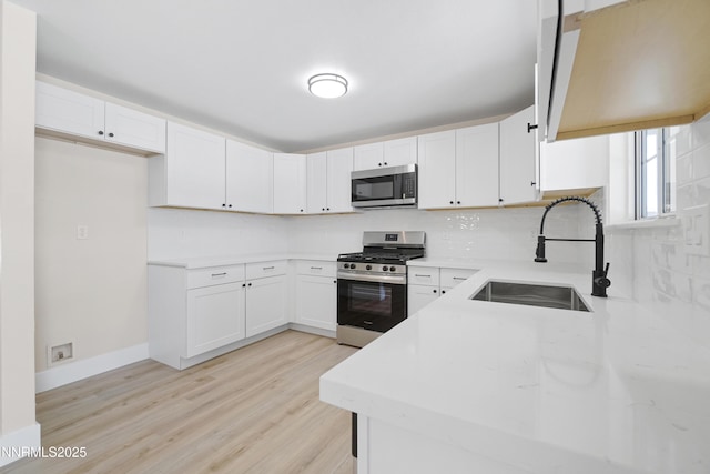 1000 Dwight Way, Dayton, NV 89403 - kitchen with stainless steel appliances, a sink, tasteful backsplash, light wood-style flooring, and white cabinetry