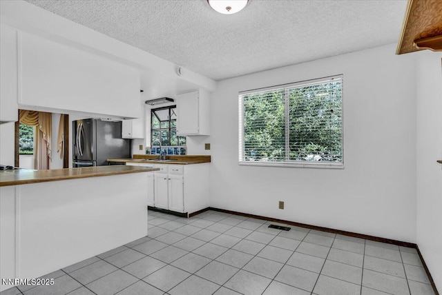 1809 Franklin Rd, Carson City, NV 89706 - kitchen featuring freestanding refrigerator, white cabinetry, a textured ceiling, a sink, and baseboards