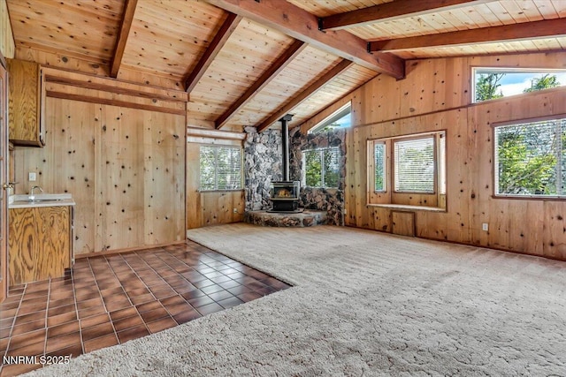 1809 Franklin Rd, Carson City, NV 89706 - unfurnished living room featuring a wood stove, wooden walls, wood ceiling, a sink, and tile patterned flooring