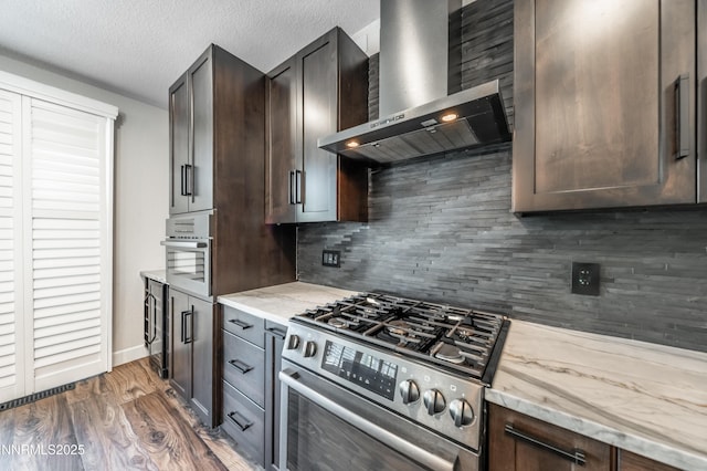 2978 Fox Trail Dr, Reno, NV 89523 - kitchen featuring gas stove, wall chimney range hood, backsplash, light stone counters, and dark brown cabinetry