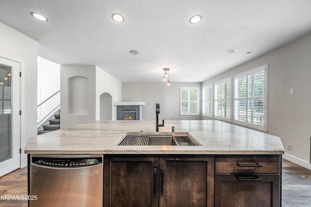 2978 Fox Trail Dr, Reno, NV 89523 - kitchen with stainless steel dishwasher, dark brown cabinets, wood finished floors, a warm lit fireplace, and recessed lighting