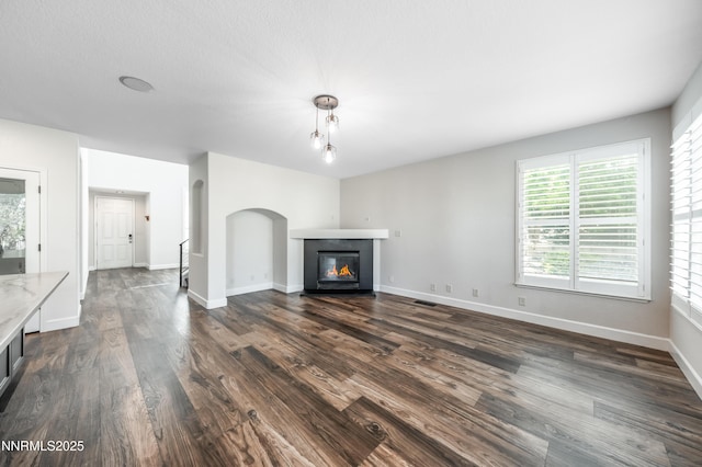 2978 Fox Trail Dr, Reno, NV 89523 - unfurnished living room featuring a glass covered fireplace, dark wood-style flooring, and arched walkways