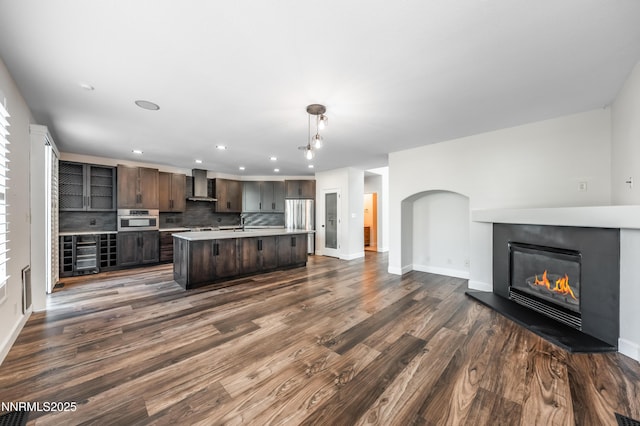 2978 Fox Trail Dr, Reno, NV 89523 - kitchen featuring wall chimney range hood, stainless steel appliances, dark brown cabinetry, open floor plan, and light countertops