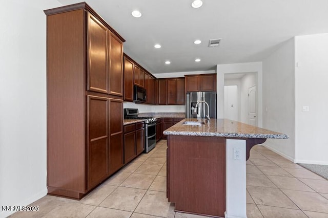 14373 Fredonia Dr, Reno, NV 89506 - kitchen with appliances with stainless steel finishes, light stone countertops, light tile patterned floors, a kitchen island with sink, and recessed lighting