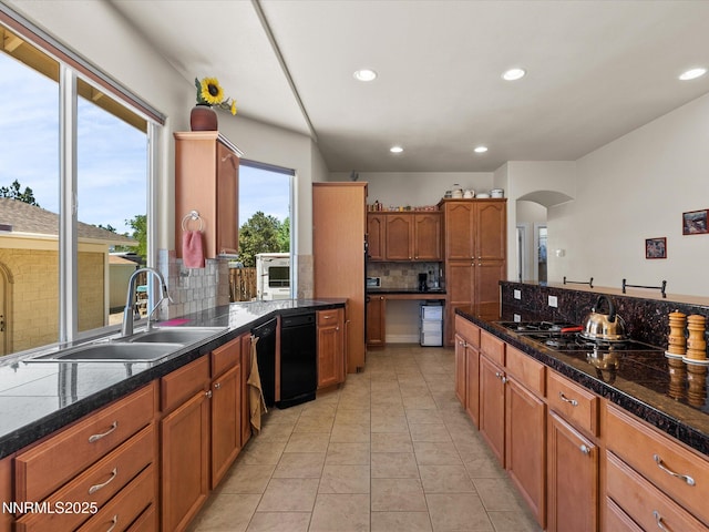4903 Killdeer Rd, Carson City, NV 89701 - kitchen with decorative backsplash, gas cooktop, brown cabinetry, arched walkways, and light tile patterned floors
