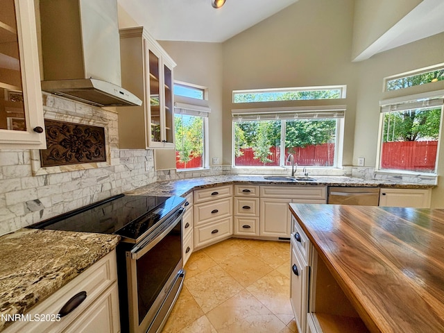 3882 Streamside Ct, Reno, NV 89519 - kitchen with stainless steel appliances, butcher block counters, wall chimney exhaust hood, high vaulted ceiling, and glass insert cabinets