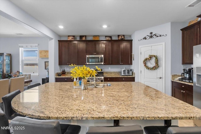 7324 Continuum Dr, Reno, NV 89506 - kitchen with appliances with stainless steel finishes, a kitchen bar, light stone counters, a spacious island, and recessed lighting