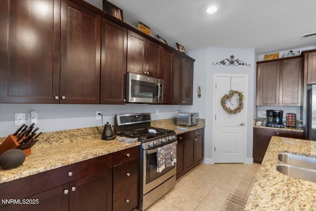 7324 Continuum Dr, Reno, NV 89506 - kitchen featuring stainless steel appliances, light stone counters, light tile patterned floors, and dark brown cabinets