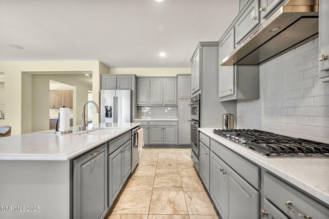 2222 Nasrullah Ln, Reno, NV 89521 - kitchen featuring gray cabinetry, stainless steel appliances, under cabinet range hood, tasteful backsplash, and a kitchen island with sink