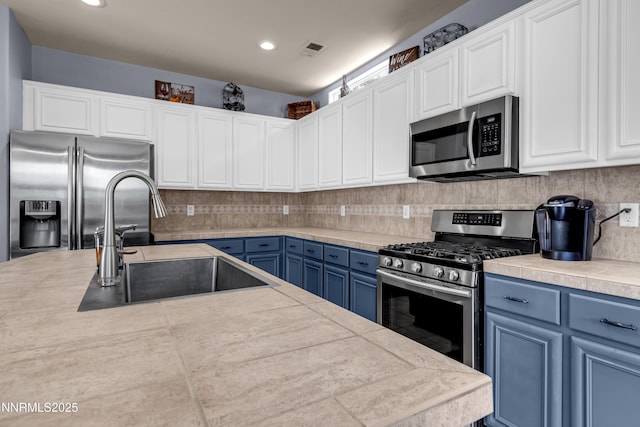 10509 Yuba Ct, Reno, NV 89521 - kitchen featuring stainless steel appliances, blue cabinets, backsplash, white cabinets, and recessed lighting