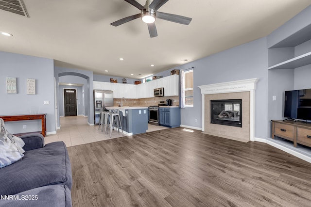 10509 Yuba Ct, Reno, NV 89521 - living room with a ceiling fan, recessed lighting, arched walkways, a tile fireplace, and light wood-type flooring