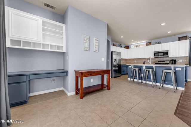 10509 Yuba Ct, Reno, NV 89521 - kitchen with stainless steel appliances, light countertops, tasteful backsplash, a breakfast bar area, and white cabinetry