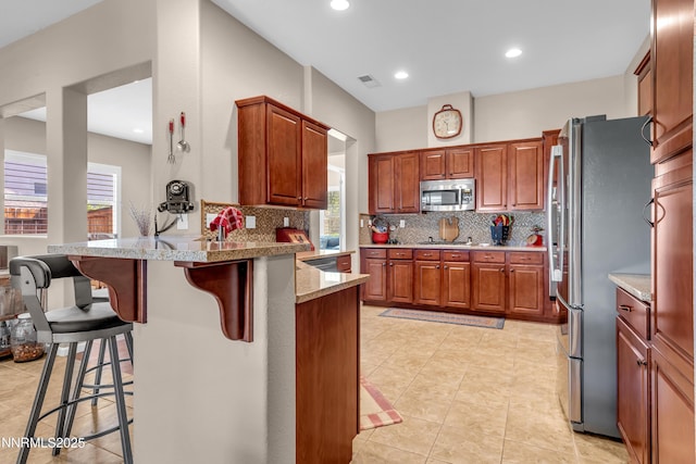4883 Brunello Dr, Sparks, NV 89436 - kitchen featuring stainless steel appliances, a peninsula, decorative backsplash, a kitchen bar, and recessed lighting