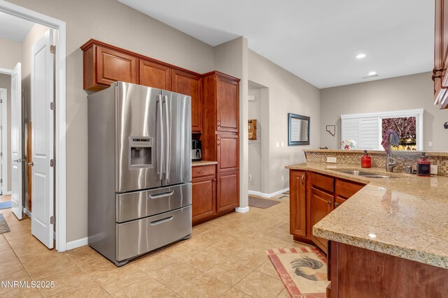 4883 Brunello Dr, Sparks, NV 89436 - kitchen featuring stainless steel fridge, light tile patterned floors, light stone counters, recessed lighting, and brown cabinetry