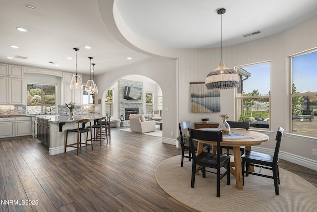 5427 Salmon River Ct, Reno, NV 89511 - dining space featuring recessed lighting, dark wood-style flooring, a fireplace, and arched walkways
