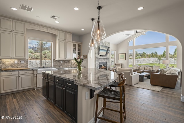 5427 Salmon River Ct, Reno, NV 89511 - kitchen with a breakfast bar, a stone fireplace, open floor plan, backsplash, and lofted ceiling