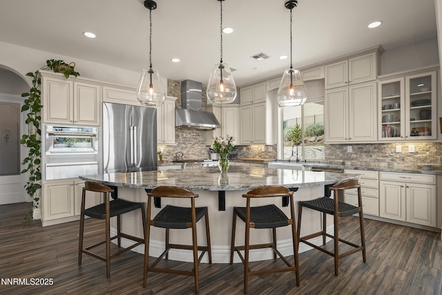 5427 Salmon River Ct, Reno, NV 89511 - kitchen featuring wall chimney exhaust hood, high end fridge, a warming drawer, decorative backsplash, and dark wood-style flooring