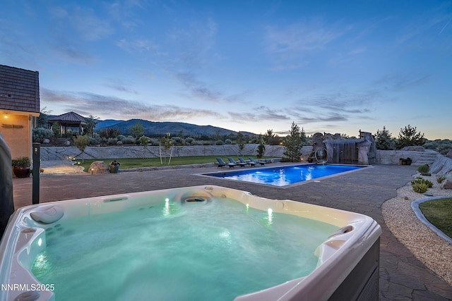 5427 Salmon River Ct, Reno, NV 89511 - pool at dusk featuring a hot tub, a mountain view, and a patio