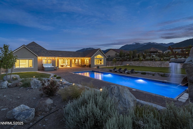 5427 Salmon River Ct, Reno, NV 89511 - pool at dusk featuring a patio area, an outdoor pool, a jacuzzi, and a mountain view