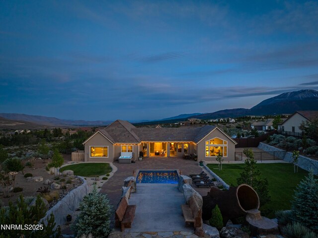 5427 Salmon River Ct, Reno, NV 89511 - back of property at dusk featuring a mountain view, a patio, a fenced backyard, stucco siding, and concrete driveway