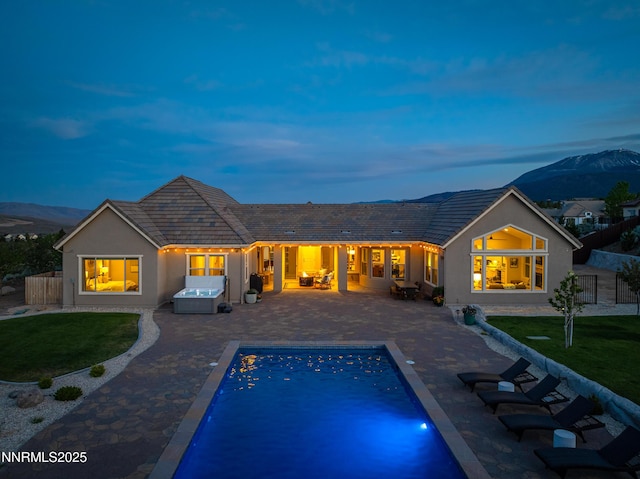 5427 Salmon River Ct, Reno, NV 89511 - back of property at dusk with a mountain view, a jacuzzi, and a patio