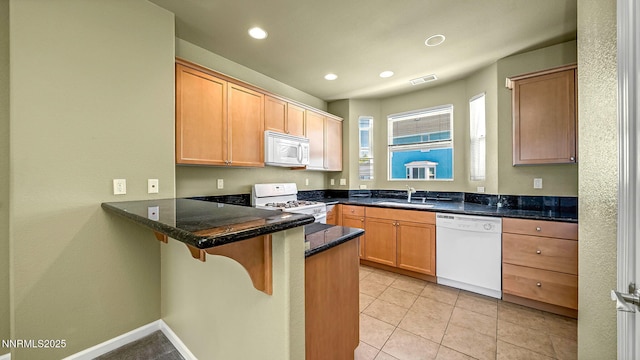 225 Gramercy Ln, Reno, NV 89509 - kitchen with white appliances, a peninsula, a breakfast bar, recessed lighting, and light tile patterned floors