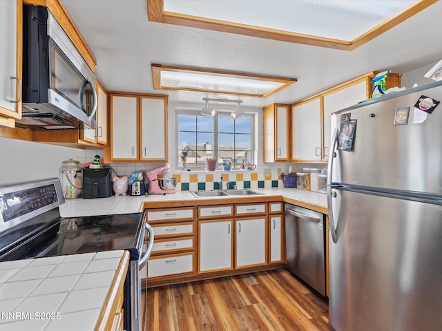 431 Michael Dr, Fallon, NV 89406 - kitchen featuring stainless steel appliances, tile counters, decorative backsplash, wood finished floors, and white cabinets